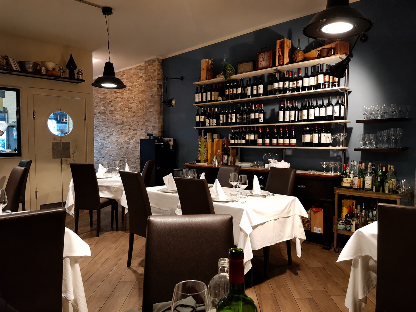 Interno della sala Beef Grill Experience con tavoli apparecchiati e parete vini